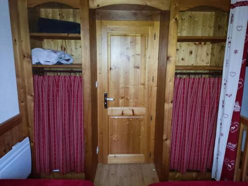 baño pequeño con paredes de madera y cortinas rojas en Le Chalet du Bucheron en Gérardmer