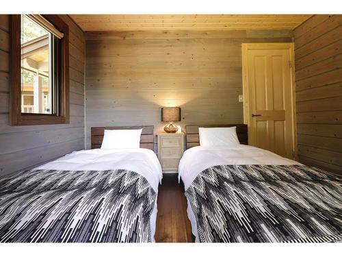 Class Vesso Tateshina - Vacation STAY 51898v في تشينو: سريرين في غرفة بجدران خشبية
