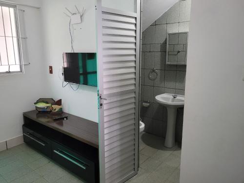 ein Bad mit einem Waschbecken, einem WC und einem TV in der Unterkunft PRAIA DE 4 ILHAS Apartamento 2 Quartos 60M Da Praia Com Vista in Bombinhas