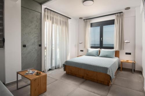 a bedroom with a bed and a large window at Vrahakia beach in Sarti