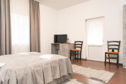 een witte kamer met een bed en 2 stoelen bij Vila Bradul in Lacu Rosu