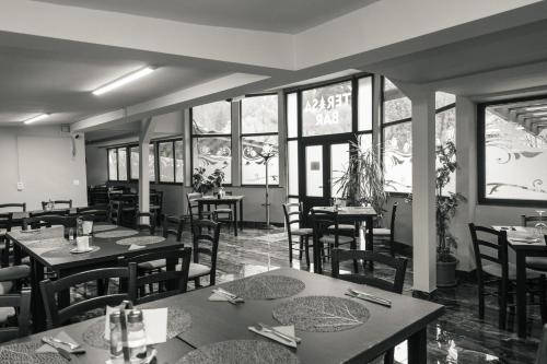 a dining room with tables and chairs and windows at Vila Bradul in Lacu Rosu