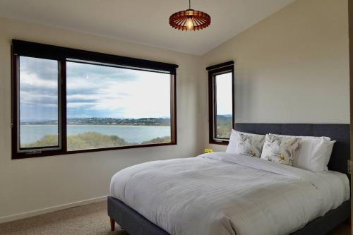 um quarto com uma cama grande e 2 janelas em Eco Waterfront Seclusion - Carlton Bluff House em Primrose Sands
