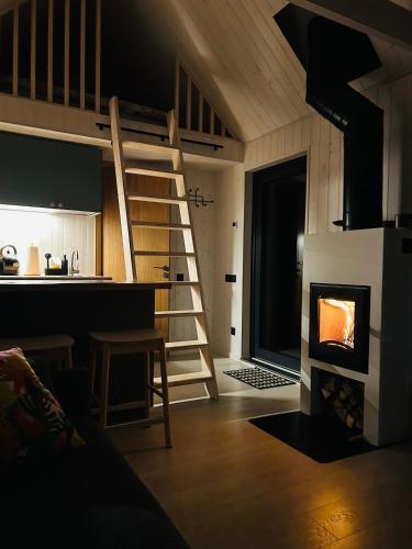 a living room with a staircase and a kitchen with a fireplace at Baltrozes in Ādaži