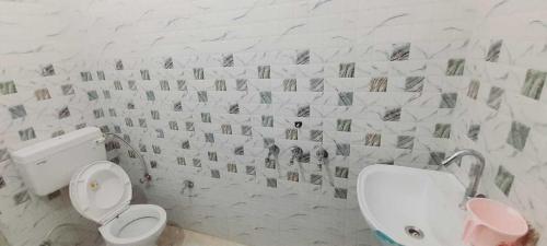 a bathroom with a toilet and a tile wall at SPOT ON Hotel Daimond Inn in Meerut
