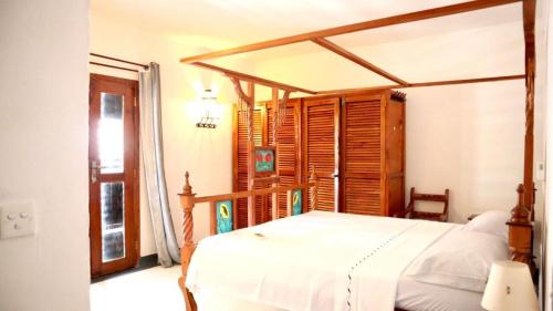een slaapkamer met een bed met een houten baldakijn bij Imani House in Malindi