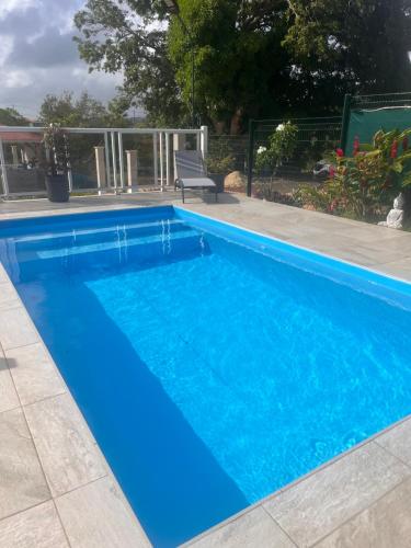 a swimming pool with blue water in a yard at Les papillons Doré in Sainte-Rose