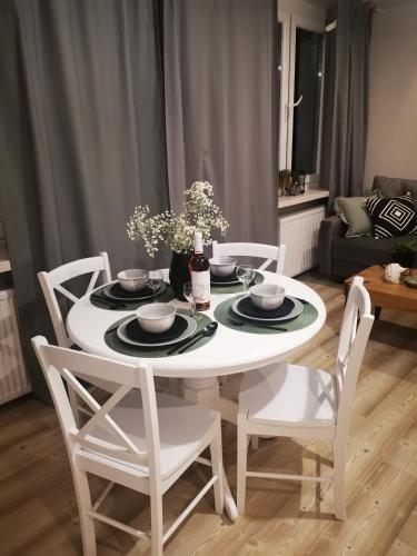 a white dining room table with white chairs and a table at Czwarte Piętro in Zamość