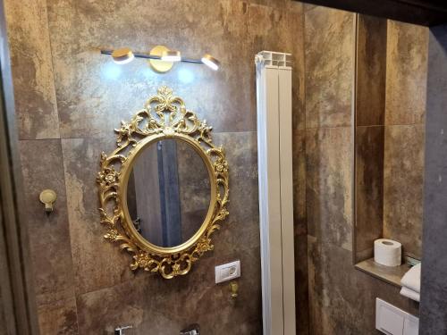 a gold mirror on a wall in a bathroom at Pensiunea Jolie in Iaşi