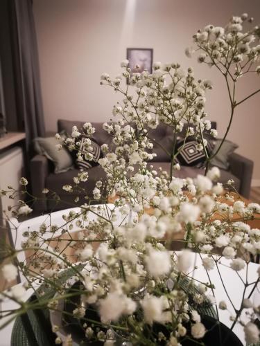 a living room with a table with white flowers at Czwarte Piętro in Zamość