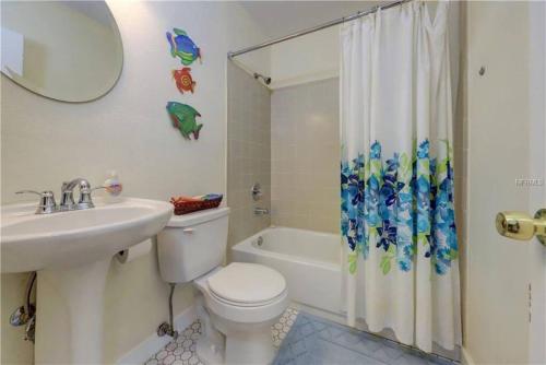 La salle de bains est pourvue de toilettes, d'un lavabo et d'un rideau de douche. dans l'établissement Large Backyard with heated pool/ Near Beach, à Clearwater Beach