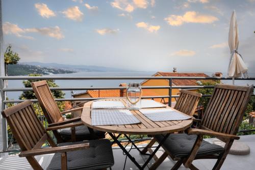 einen Holztisch und Stühle auf dem Balkon in der Unterkunft New cosy apartments with private parking in Opatija