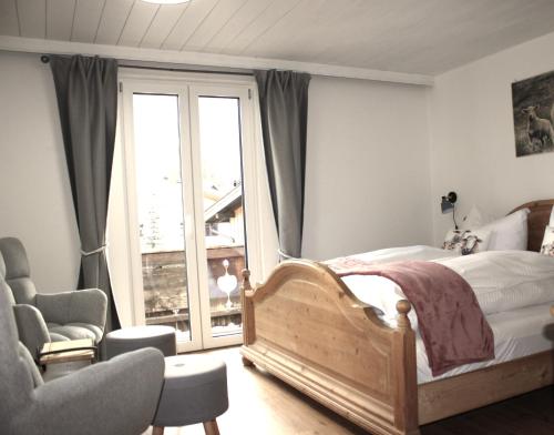 um quarto com uma cama, uma cadeira e uma janela em Haus Heimatfrieden Mittenwald em Mittenwald
