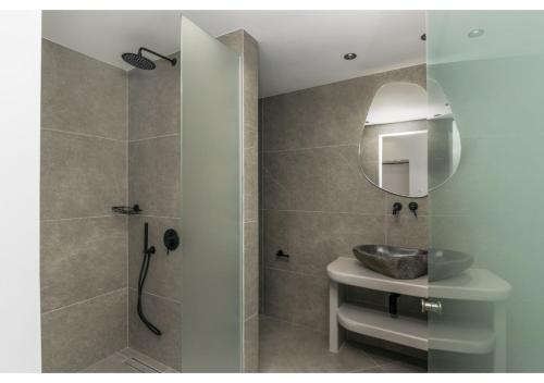 een badkamer met een wastafel en een douche met een spiegel bij Leuki Villa Milos in Adamas