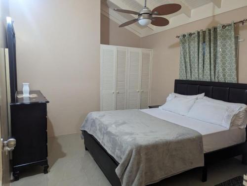 sypialnia z łóżkiem i wentylatorem sufitowym w obiekcie La Palmera w mieście Saint Annʼs Bay