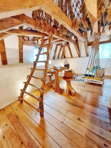 a room with a wooden floor with a wooden ladder at Nid d amoureux in La Roque-Gageac