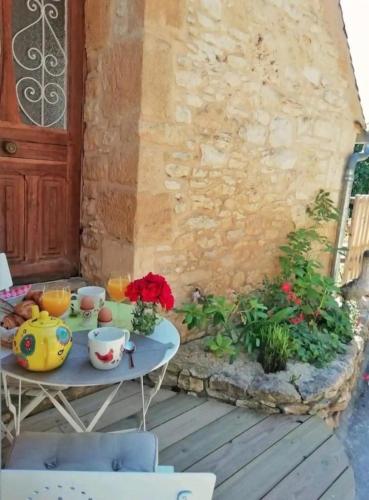 einen Tisch mit Tassen und Blumen auf einer Terrasse in der Unterkunft Nid d amoureux in La Roque-Gageac