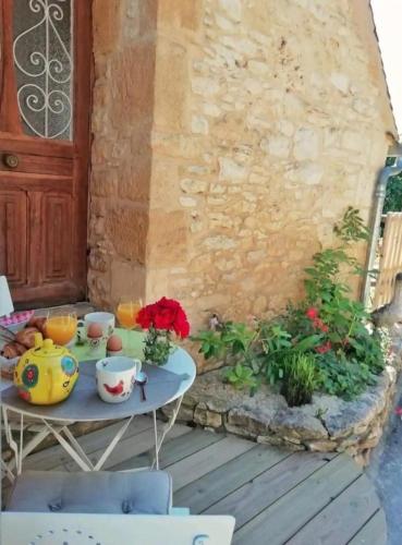 - une table avec des tasses et des fleurs sur la terrasse dans l'établissement Nid d amoureux, à La Roque-Gageac