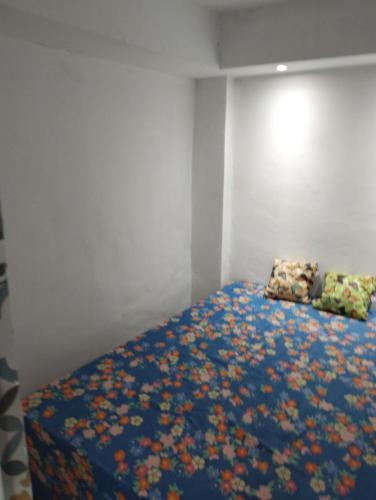 um quarto com uma cama com um cobertor azul com flores em Casa praia cabuçu - azul com piscina em Saubara