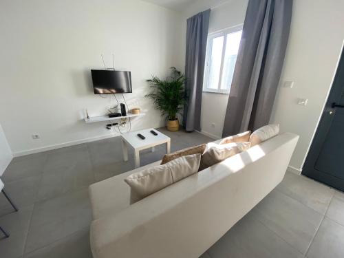 a living room with a white couch and a tv at Casa Cova da Onça in Olhão