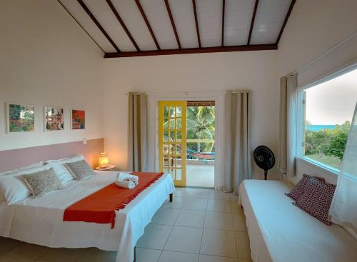 クムルサティバにあるCanto do Mar - Apartamentos e Casa com vista pro Mar - Cumuruxatibaのベッドが2つと大きな窓がある寝室