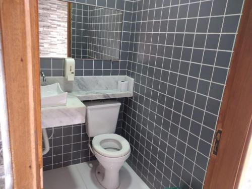 a blue tiled bathroom with a toilet and a sink at Piscina 6 QUARTOS 300mPRAIA jardim churrasqueira 16 PESSOAS garagem 3 carros Monitoramento 24 horas Mesa de sinuca in Itanhaém