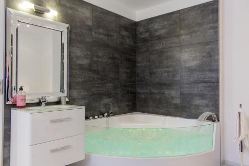 y baño con bañera, lavabo y espejo. en MY SWEET HOMES - Appartements avec SPA, en Colmar