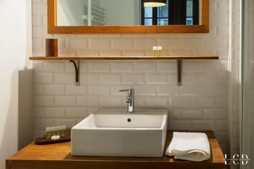 y baño con lavabo blanco y espejo. en Au roi lion, place Saint Michel, en Dijon