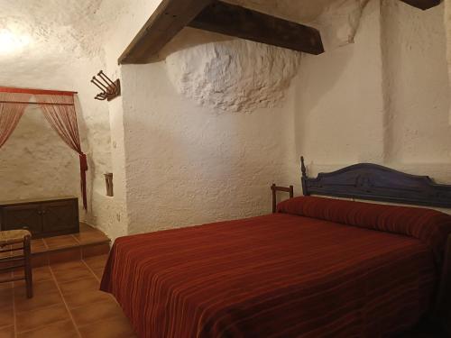 1 dormitorio con cama roja y chimenea en Las Cuevas Del Abismo, en Alcalá del Júcar