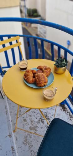 une table jaune avec une assiette de pâtisseries dans l'établissement Appartement contemporain le Vendome à 90m de la plage, au Grau-du-Roi