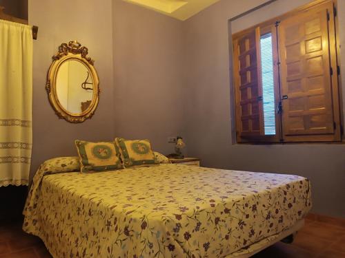 1 dormitorio con cama con espejo y ventana en Las Cuevas Del Abismo, en Alcalá del Júcar