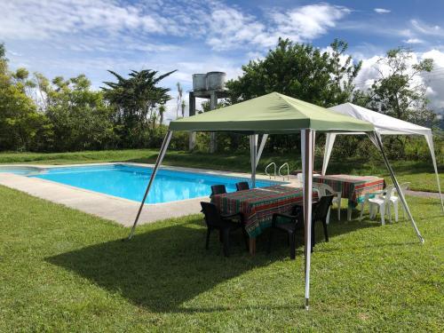 einen Tisch und Stühle unter einem Zelt neben einem Pool in der Unterkunft Finca Fundadores in Chachagüí