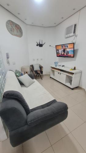 1 dormitorio con 1 cama grande y TV en la pared en Guarujá enseada sp, en Guarujá