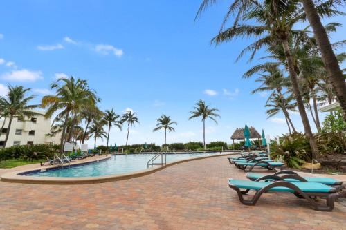 a swimming pool with chaise lounges and palm trees at Tides on Hollywood Beach in Hollywood