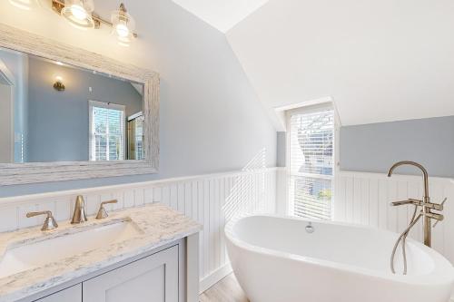 a white bathroom with a tub and a sink at Victorian by the Sea in Oak Bluffs