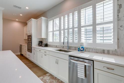 a kitchen with white cabinets and a sink and a window at Modern Redington Beach Townhome Steps to Beach! in St Pete Beach
