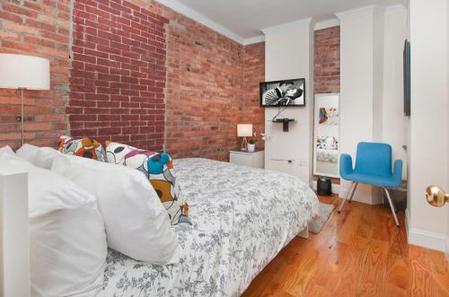 Modern 3BR Apartment in NYC في نيويورك: غرفة نوم بسرير وجدار من الطوب