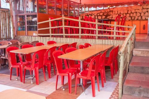 a room with tables and red chairs and stairs at Flagship Key 2 Heaven in Ooty
