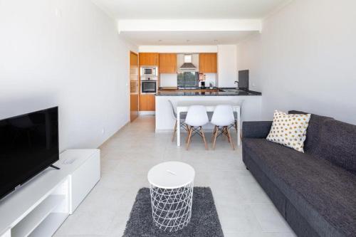 a living room with a couch and a kitchen at Appartement Vista das ondas in Olhos de Água