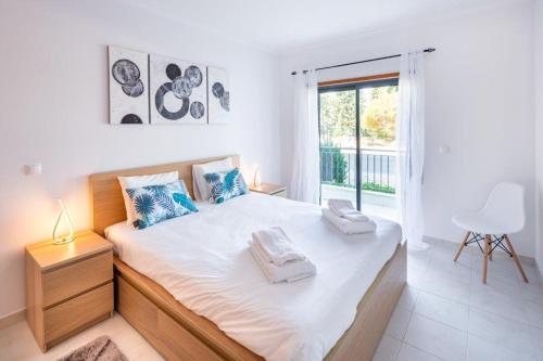 a white bedroom with a large bed and a window at Appartement Vista das ondas in Olhos de Água