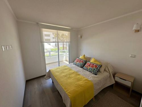 1 dormitorio con 1 cama con sábanas amarillas y ventana en Depto nuevo a pasos de la playa, en La Serena