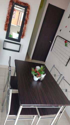a dining room table with two plants and a mirror at Apartamento vacacional con piscina y parqueadero in Ibagué