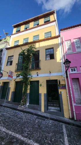 a yellow building with a tree in front of it at Tamboleiros Hotel & Hostel in Salvador