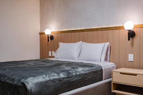 a bed in a hotel room with two lights on the wall at Escandon Suites by Escajal Rooms in Mexico City