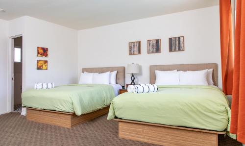 2 letti in una camera d'albergo con lenzuola verdi di The Skylark, a Palm Springs Hotel a Palm Springs