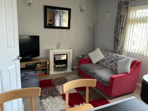a living room with a red couch and a tv at 1st Floor Hillview 2 bedrooms central location in Brean