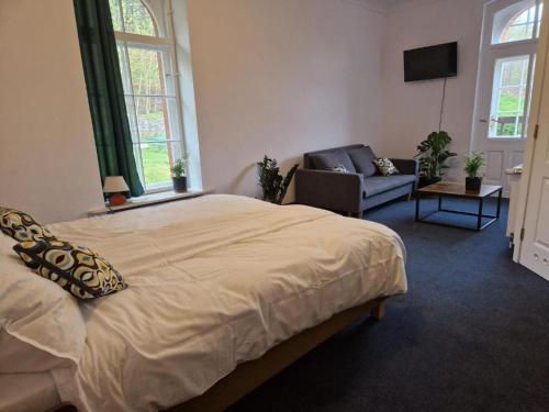 a bedroom with a bed and a couch and a chair at Hotel Krasnoludki in Sosnówka