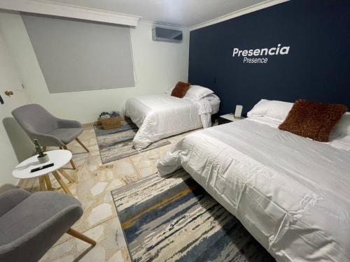 een slaapkamer met 2 bedden en een stoel en een projectiescherm bij Habitación Privada Laureles, Suit Medellin Jacuzzi in Medellín