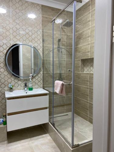 een badkamer met een douche, een wastafel en een spiegel bij ЖК Керемет in Karagandy