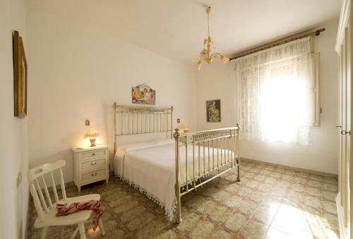 Un dormitorio con una cama y una silla y una ventana. en Villa Paradiso, en Castelluzzo